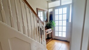 Un escalier en bois mène à une pièce dotée d’une grande fenêtre et d’un ventilateur de plafond.