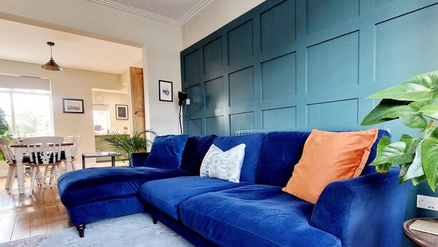 Un salon avec un canapé d’angle bleu, un tapis à motifs et un mur d’accent de couleur turquoise.
