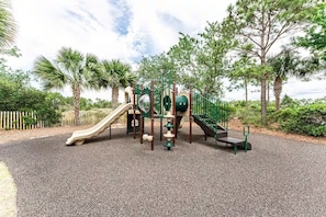 A playground with a slide, climbing structures, and a bench.