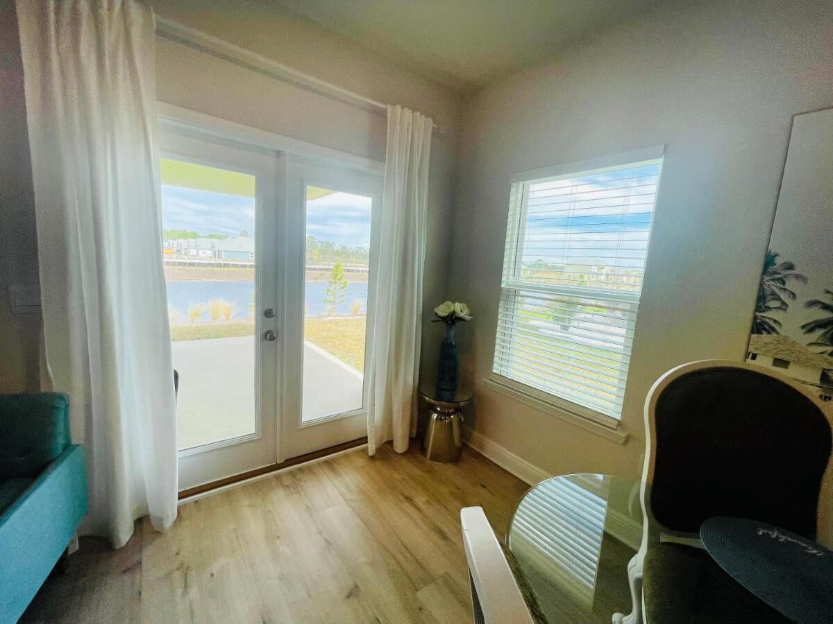 Ein Zimmer mit einer Schiebetür zu einem Außenbereich, einem Tischchen mit einer Vase und einem Stuhl.