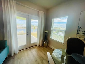 Ein Zimmer mit einer Schiebetür zu einem Außenbereich, einem Tischchen mit einer Vase und einem Stuhl.
