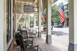 Ein überdachter Außenbereich mit Tischen und Stühlen, eine amerikanische Flagge und ein Schild mit der Aufschrift 'The Mill Mercantile & Social'.