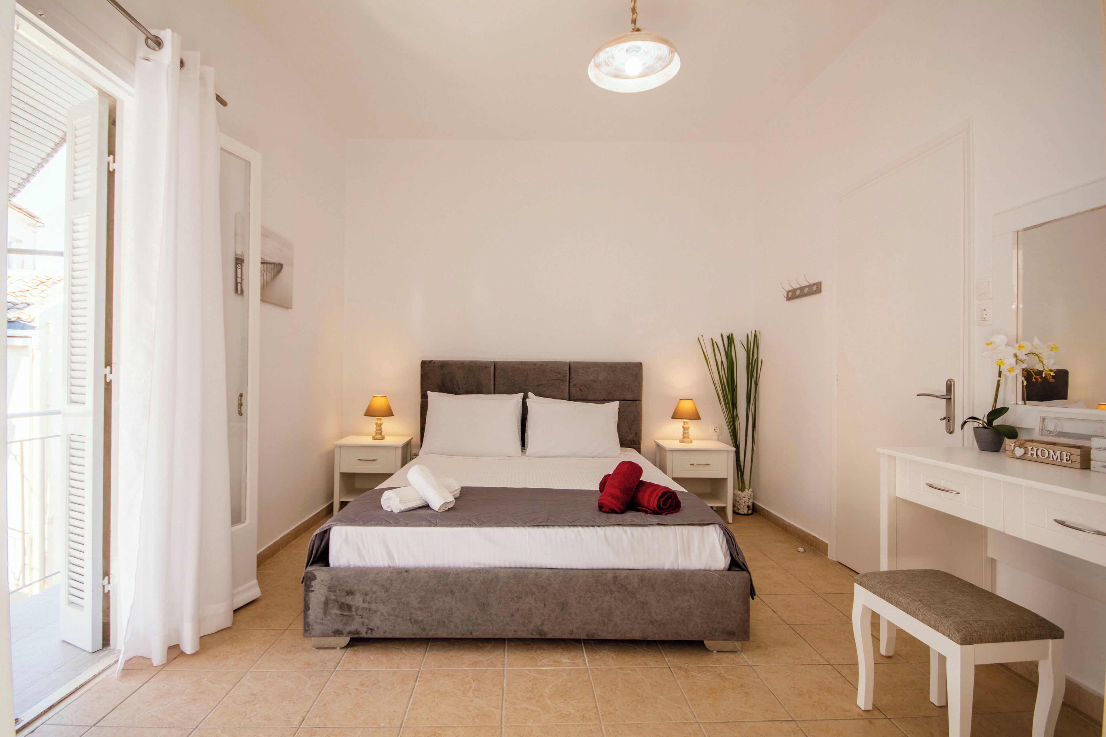Une chambre bien rangée, avec un lit, des tables de chevet, un bureau et un banc.
