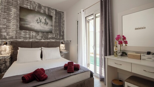 Un dormitorio con cama, escritorio, silla, espejo y ventana con cortinas.