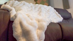Ein braunes Leder Sofa mit einer weißen, flauschigen Decke.