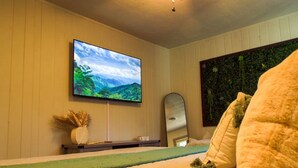 Ein Schlafzimmer mit einem Bett, einem an der Wand montierten Fernseher, einem Spiegel und einer Wanddekoration.