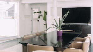 A modern dining area with a glass table, leather chairs, and potted plants. - Maison Work & Travel 7 - Palermo  (Buenos Aires)