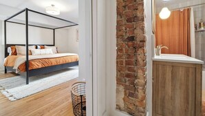 A bedroom with a four-poster bed, a wooden floor, and a brick wall. - Montrose Manor- In the heart of Belmont! (Charlottesville)