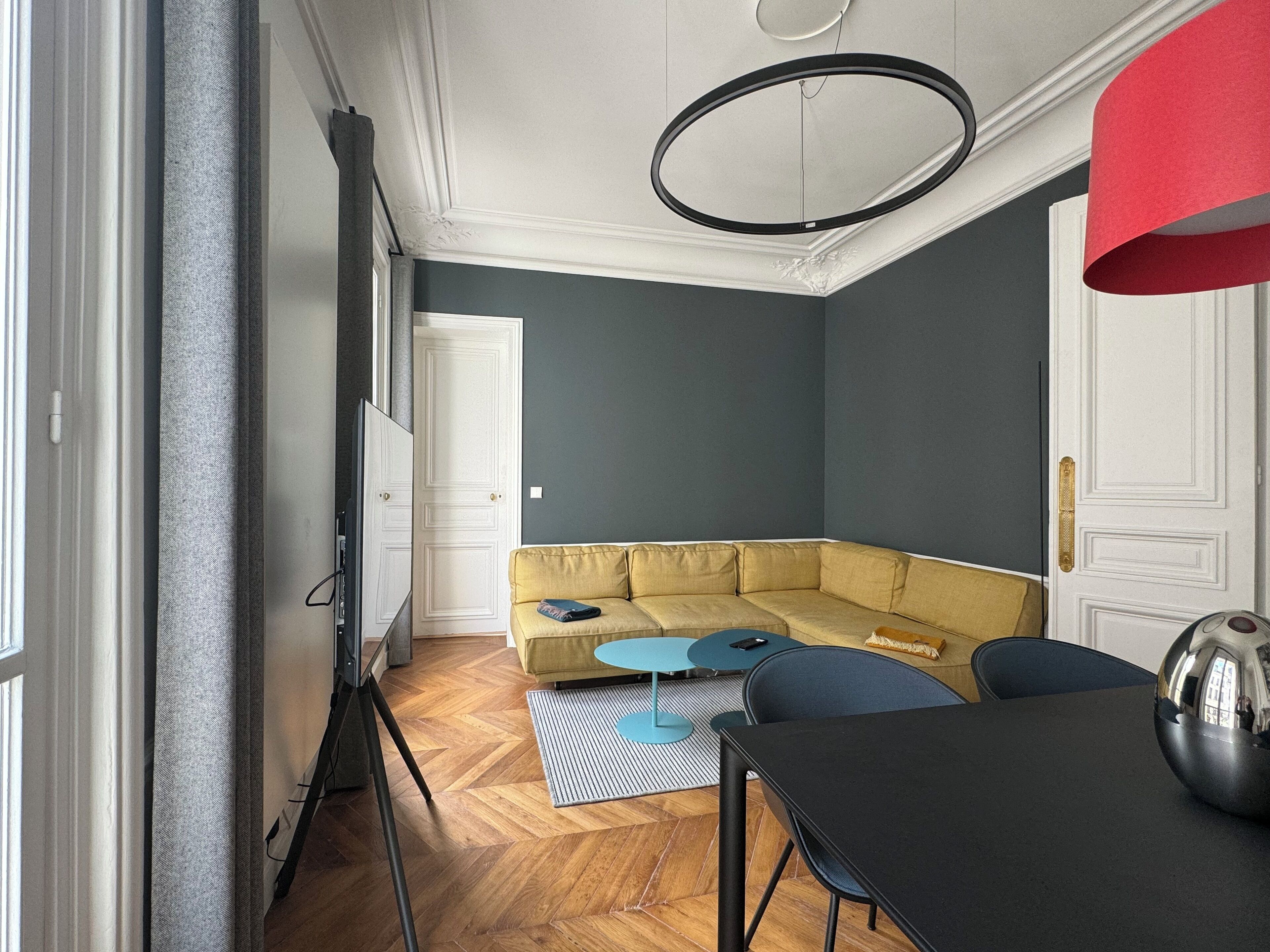 Ein modernes Wohnzimmer mit einem gelben Sofa, einem kleinen runden Tisch und einem schwarzen Esstisch.