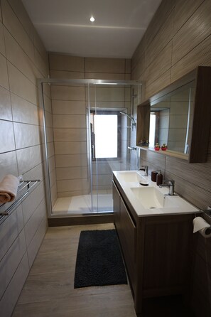 A modern bathroom with a glass-enclosed shower, a vanity with a mirror, and a towel rack.