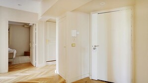 A hallway with white doors, a telephone, and a bed in the background.
