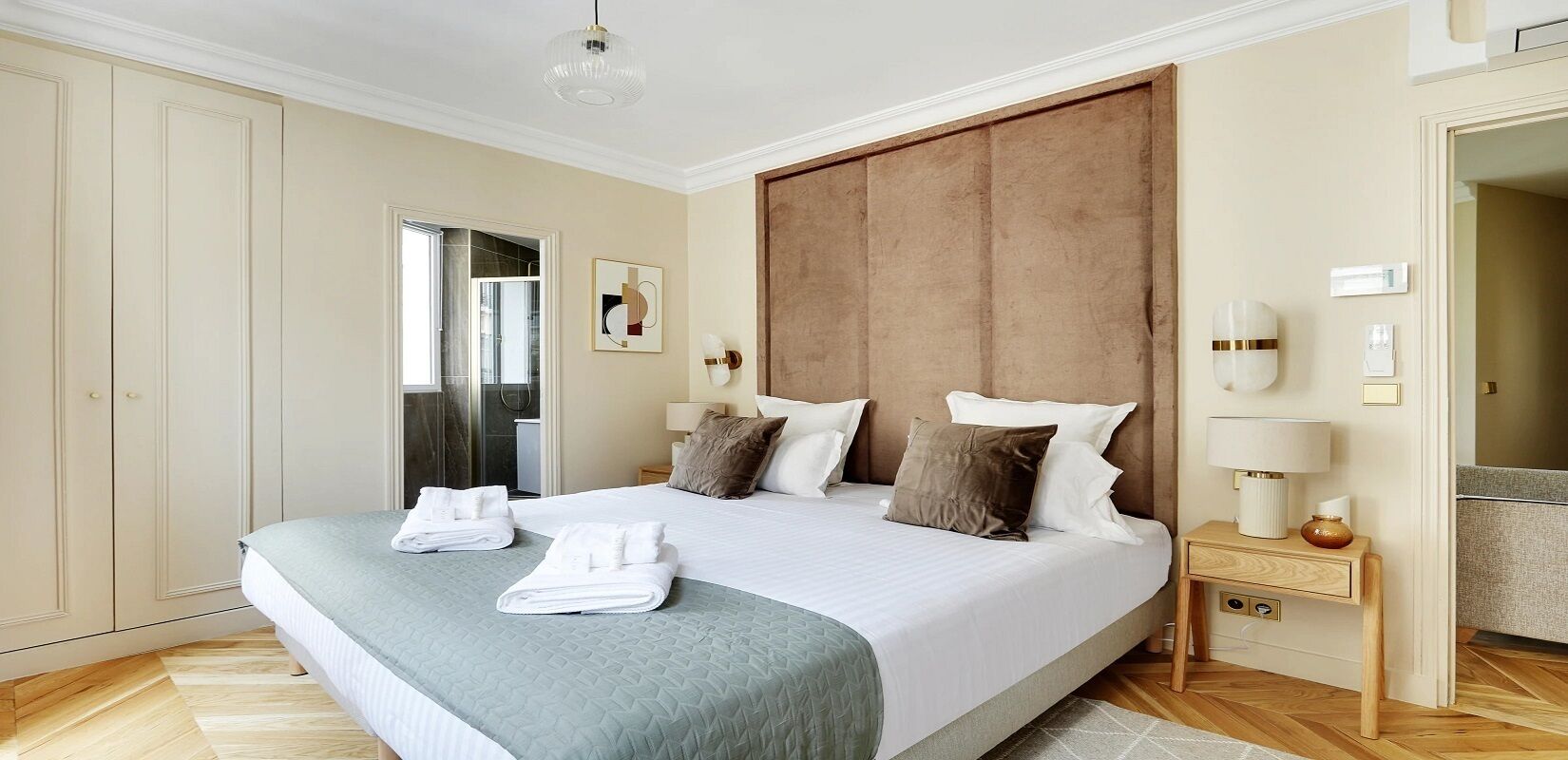 Un dormitorio amplio con una cama grande, cabecera de madera y una mesita de noche con lámpara.