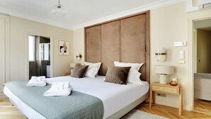 A spacious bedroom with a large bed, a wooden headboard, and a bedside table with a lamp.