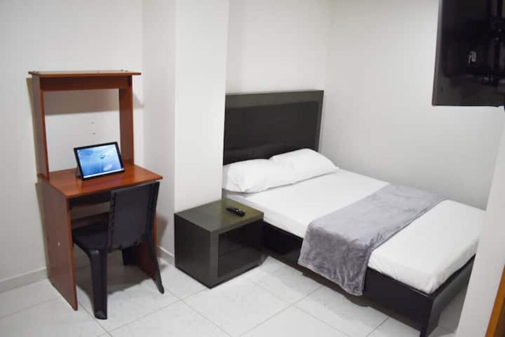 Una camera da letto piccola e ordinata, con un letto, una scrivania e una sedia.