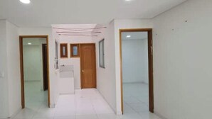 A hallway with white walls, a tiled floor, and wooden doors.
