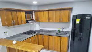 A kitchen with wooden cabinets, a black refrigerator, a sink, and a stove.