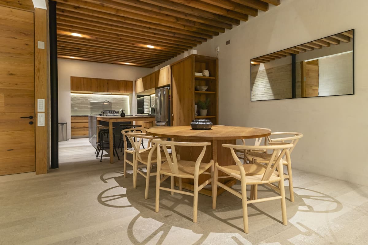A modern kitchen with wooden cabinets, a round dining table, and six chairs.