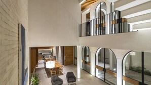 A spacious, modern interior with a high ceiling, a dining area, and a balcony with a railing. - A Ndigo San Miguel (San Miguel de Allende)
