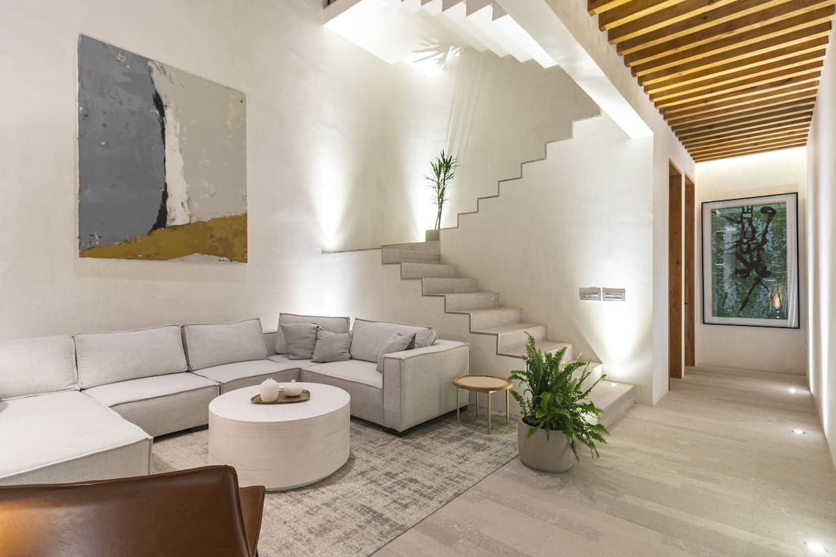 A modern living room with a sectional sofa, a round coffee table, and a staircase leading to another level.