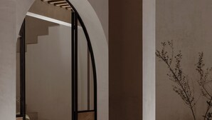An interior corridor with arched doorways, a staircase, and a potted plant. - A Ndigo San Miguel (San Miguel de Allende)