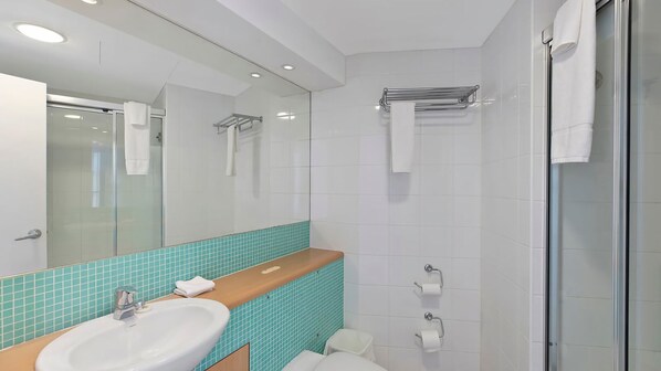Een moderne badkamer met een wastafel, spiegel, douche en toilet.
