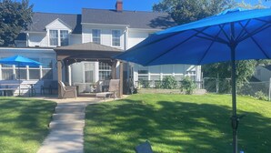 A backyard with a patio area, a covered seating area, and a glass table with a water bottle.
