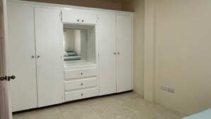 Et soveværelse med en stor garderobe, en seng og et lille siddeområde.