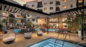 A rooftop pool area with lounge chairs and a bar.