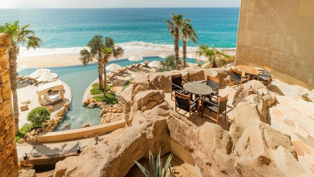 Un resort con piscina, palmeras y vistas a la playa y al océano.