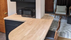 A compact kitchen with dark cabinets, a microwave, and a wooden countertop.