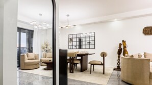 Una sala moderna con comedor, un espejo grande y una escultura decorativa.