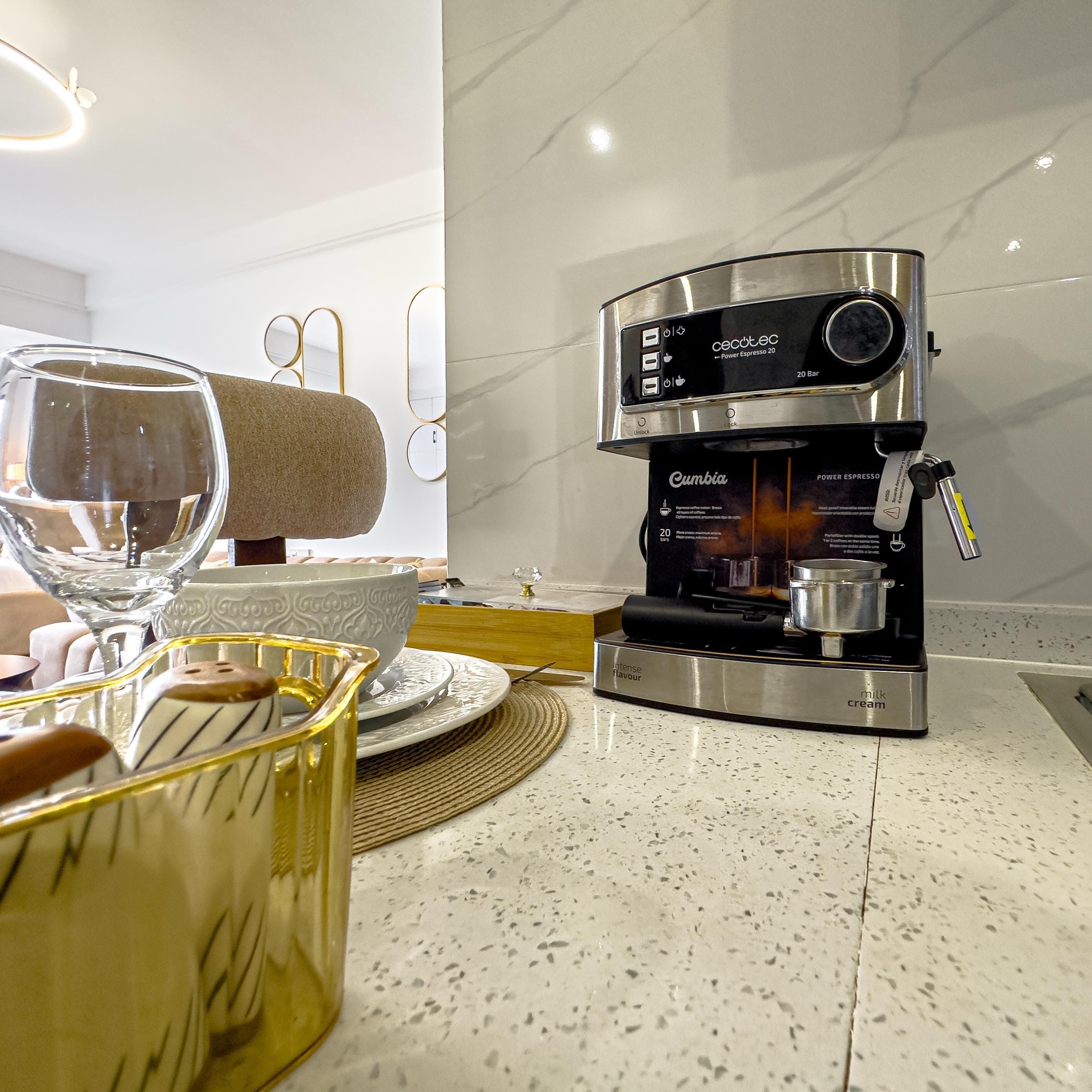 Una cocina moderna con una máquina de café Cumbia Power Espresso 20, una jarra de vidrio y un tazón sobre la encimera.