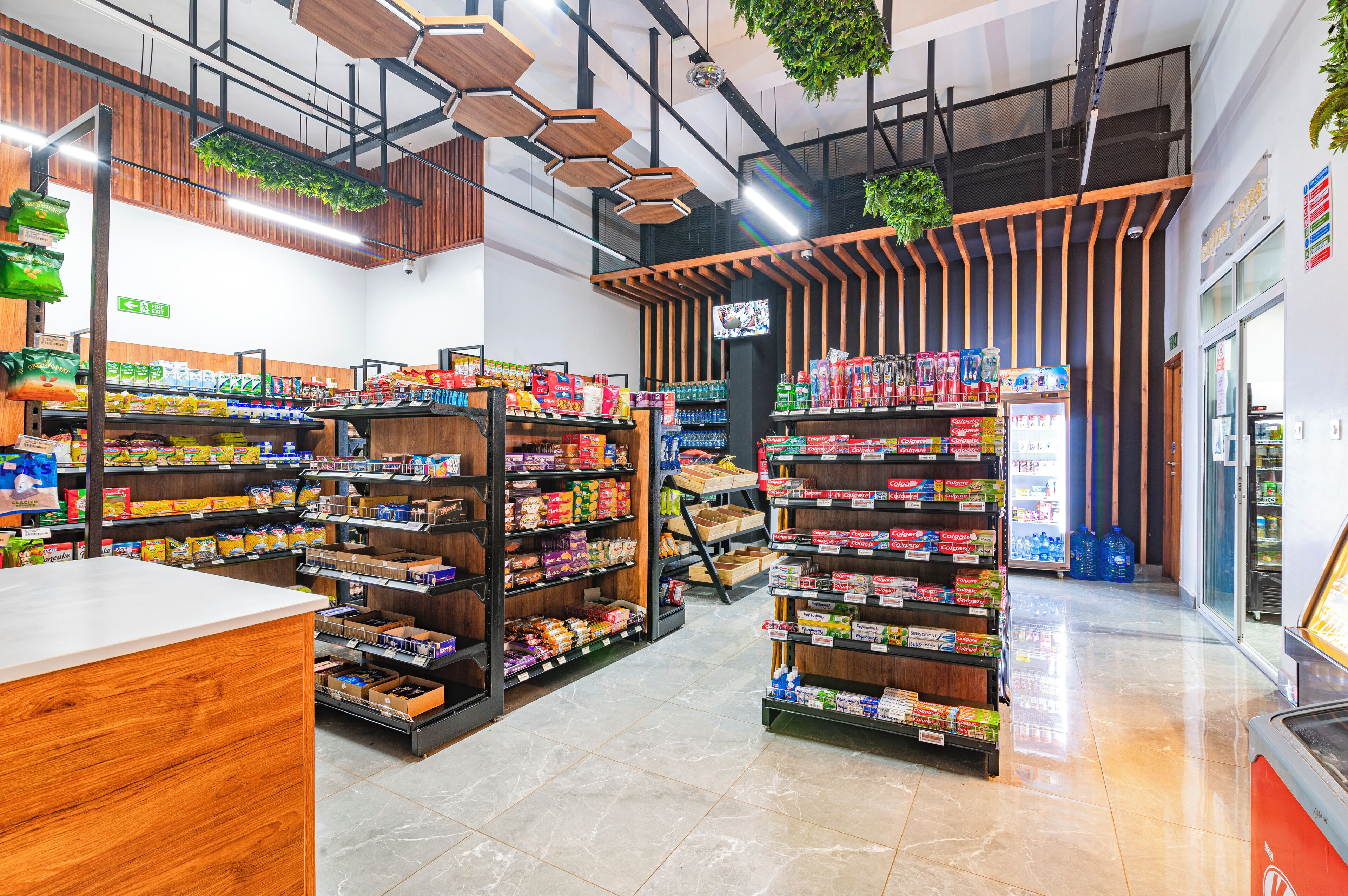 L’intérieur d’une épicerie moderne, avec des étagères en bois, un comptoir central et une grande variété de produits.