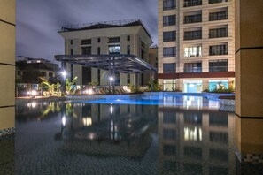 A modern hotel with a swimming pool, a covered outdoor area, and a multi-story building in the background. - Da'Bryl Luxury Suites (Nairobi)