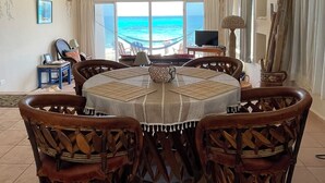 A dining area with a round table, wicker chairs, and a view of the ocean. - SEA CLIFF, 4-bedroom Economical, Oceanfront House, Isla Mujeres (Isla Mujeres)