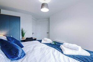 Een hotelkamer met een bed, een bureau, een stoel, een deur en een plant.