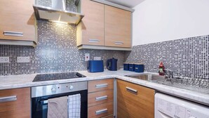 Una cocina moderna con extractor de acero inoxidable, lavavajillas y salpicadero de azulejos.