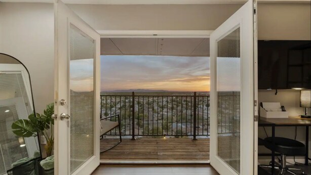 Un balcón abierto con vistas a un paisaje urbano al atardecer.