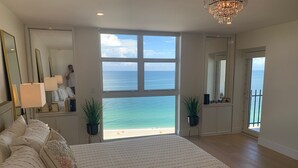 A spacious bedroom with a large bed, a view of the sea, and a balcony.
