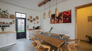 A modern kitchen with a wooden dining table, white cabinets, and a black door.