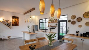 Eine moderne Küche mit Holzausstattung, ein Essbereich mit einem Holztisch und ein großes Fenster.