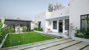Ein modernes Haus mit gepflegtem Rasen, einem Betonweg und Kübelpflanzen.