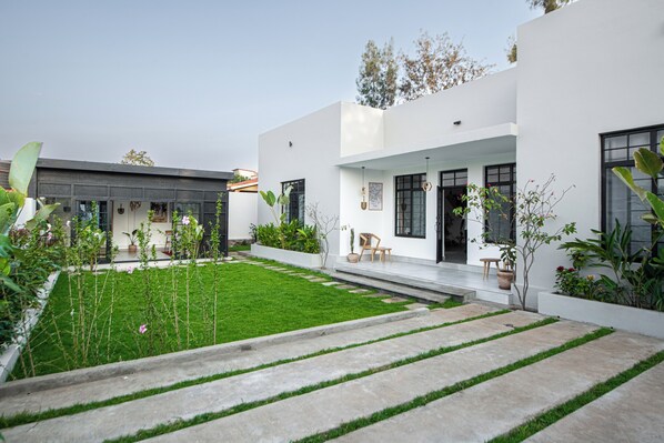 Una casa moderna con césped cuidado, un camino de hormigón y plantas en macetas.