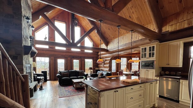 A spacious log cabin interior with a large kitchen, dining area, and living room.