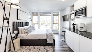 A modern bedroom with a large bed, bedside lamps, and a view of the outdoors.