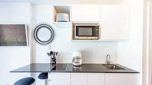 A modern kitchen with white cabinets, a black countertop, a microwave, a coffee maker, and a sink.