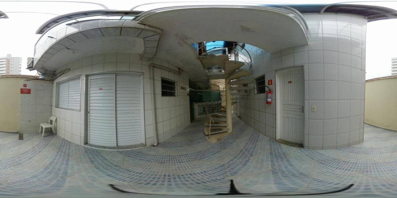 A corridor with closed doors, a spiral staircase, and a small white chair.