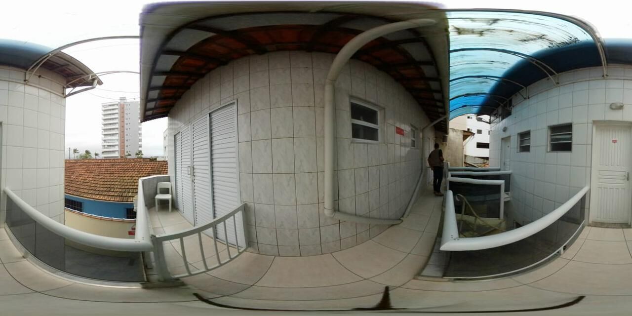 A panoramic view of a building with a curved facade, a staircase, and a small window.