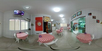 Un restaurante con manteles a cuadros, sillas blancas y un televisor en la pared.