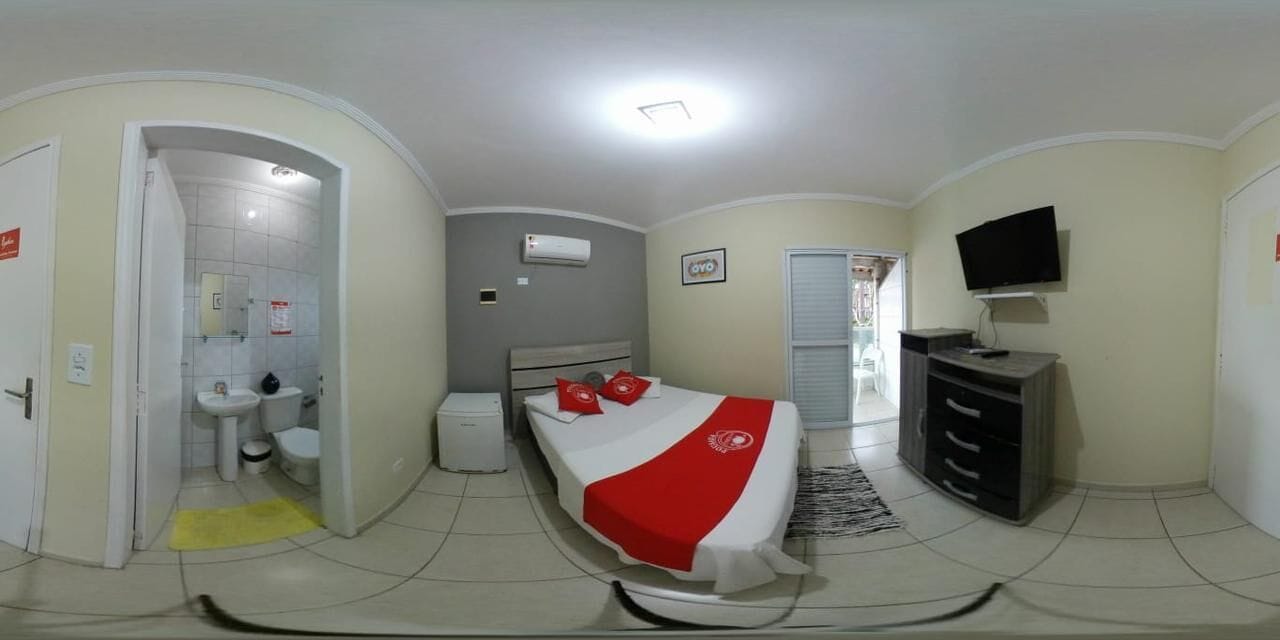 A bedroom with a bed, a TV, a dresser, and a bathroom.